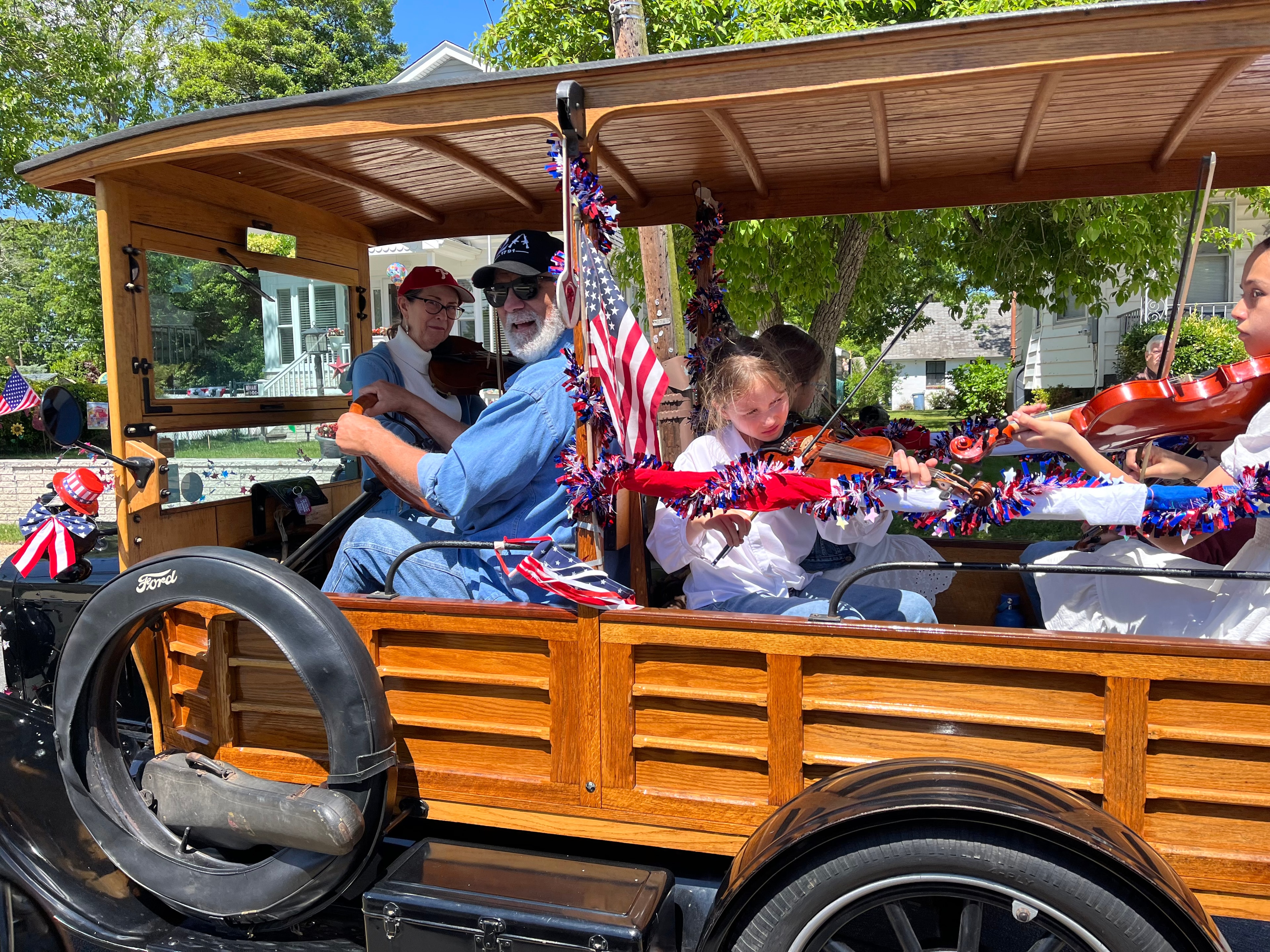 Fiddle Club playing in a 4th of July parade on a vintage Ford truck